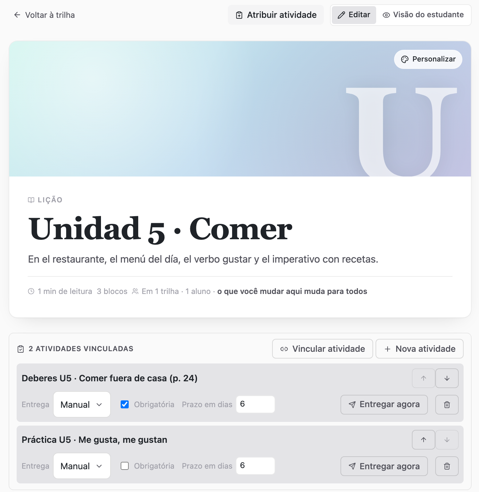 O editor de uma lição: capa, título «Unidad 5 · Comer», o aviso «em 1 trilha · 1 aluno · o que você mudar aqui muda para todos» e duas atividades vinculadas à lição.